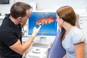 A dental professional showing a person's tooth decay on a computer screen