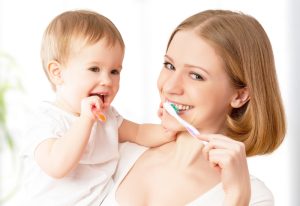 A mother and her child both brushing their teeth