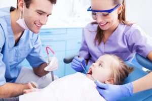 Male and female dental hygienists helping a child patient