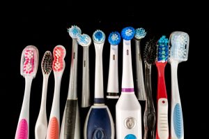 A black background that has various types of toothbrushes and electric toothbrushes all in a row.