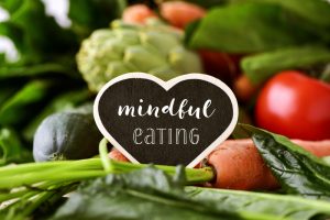 A heart cutout that says "mindful eating" on it as it sits in a pile of salad.