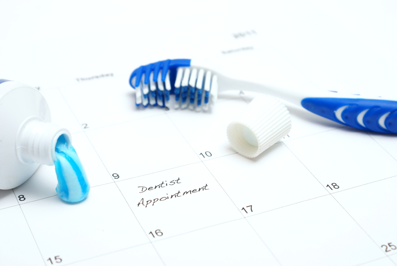 Calendar that says "dentist appointment" with toothbrush and open toothpaste beside it.