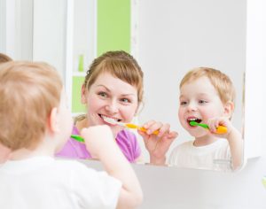 A mother and child brushing their teeth together
