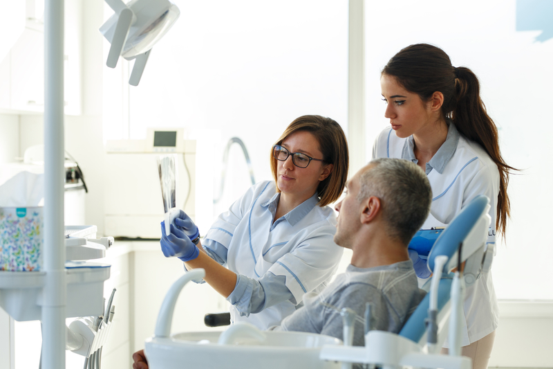 Dental patient in chair talking with dentist and assistant about his X-rays.