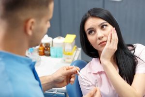 A woman patient with tooth pain speaking with a dental professional
