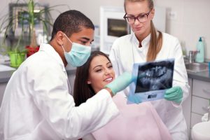 Dentist and hygienist that are looking at dental x-rays with a patient