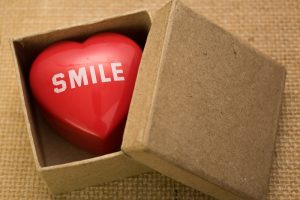 A brown, plain gift box that has a heart inside of it that says "smile" on it.