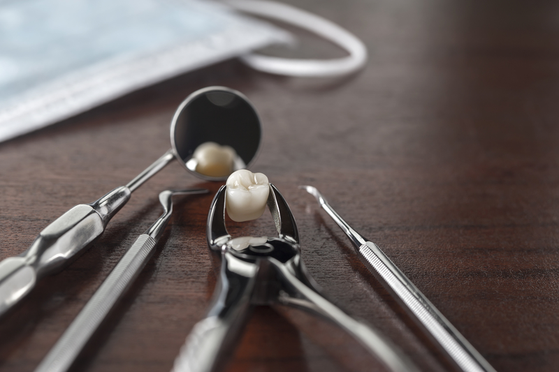 Tooth extracting dental tools with a tooth sitting near a mirror and forceps.